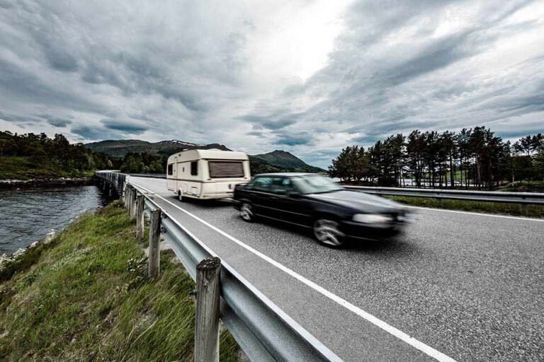 Bil der kører med trailer på vej